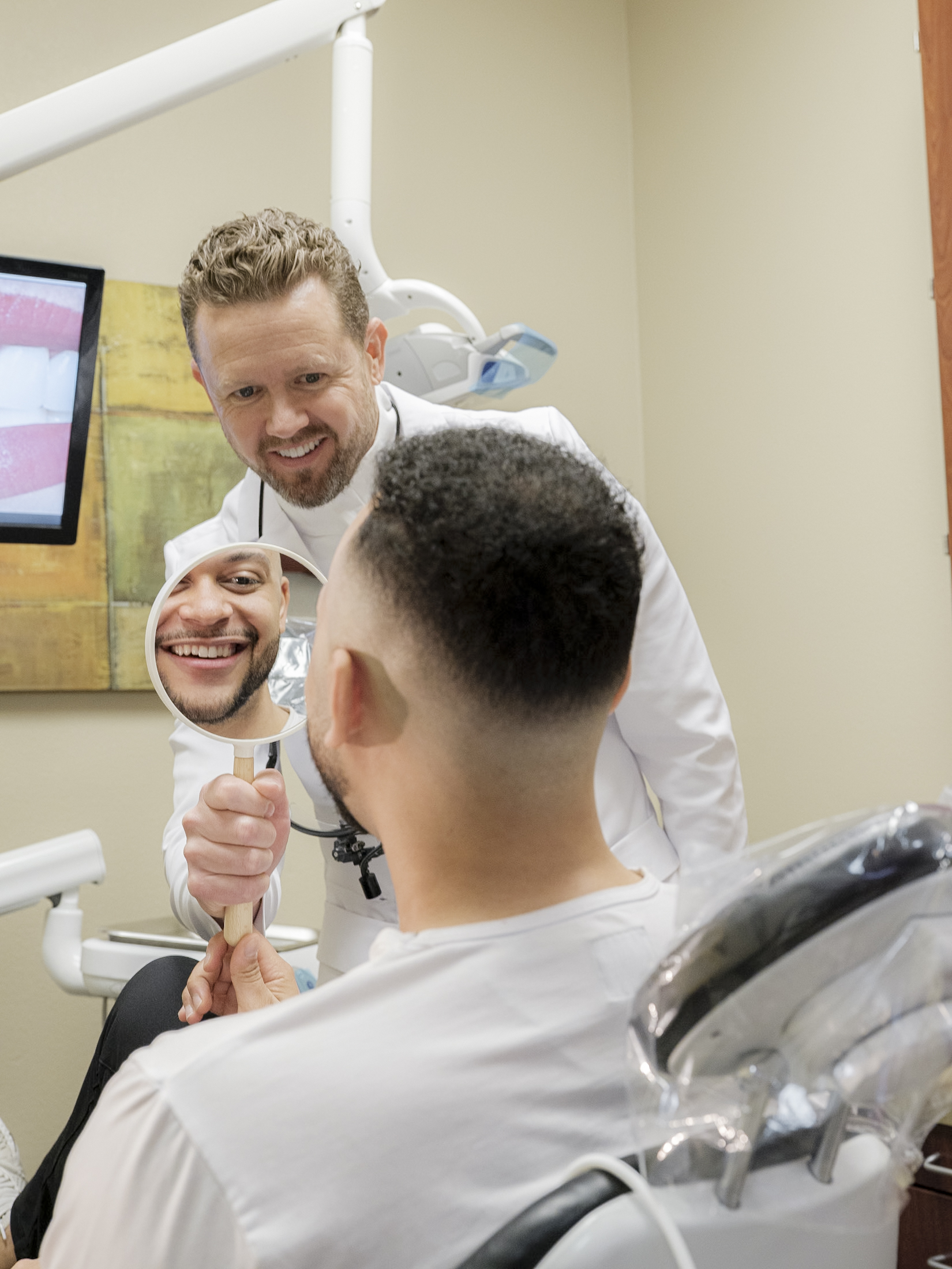 Dentist showing a patient his smile with a hand mirror in a treatment room at Modern Dental Care