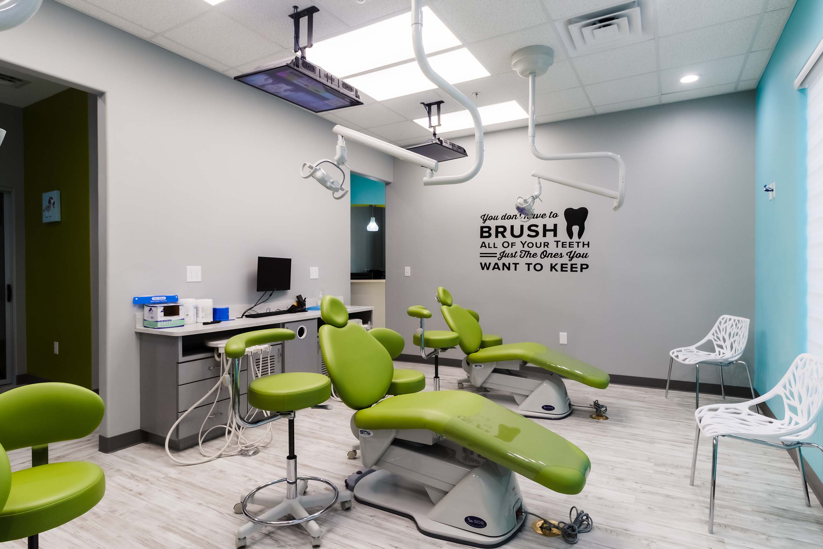 Treatment room with green dental chairs and motivational wall decal at Castle Hills Pediatric Dentistry in Carrollton, TX