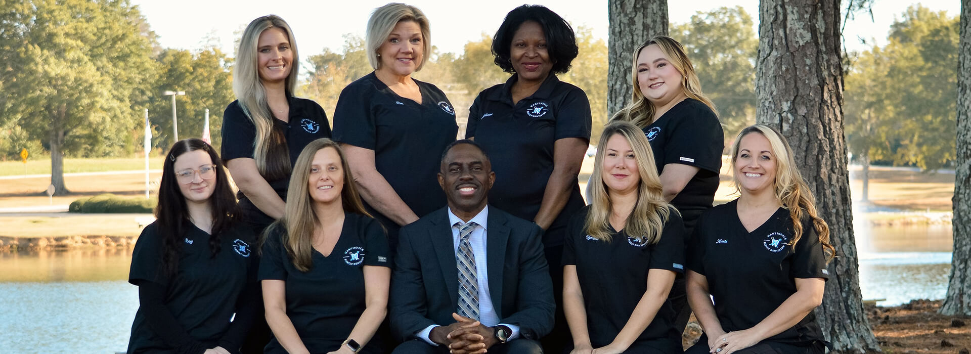 Team of dentists and staff posing outdoors by a pond at Martindale Family Dentistry in Griffin, GA