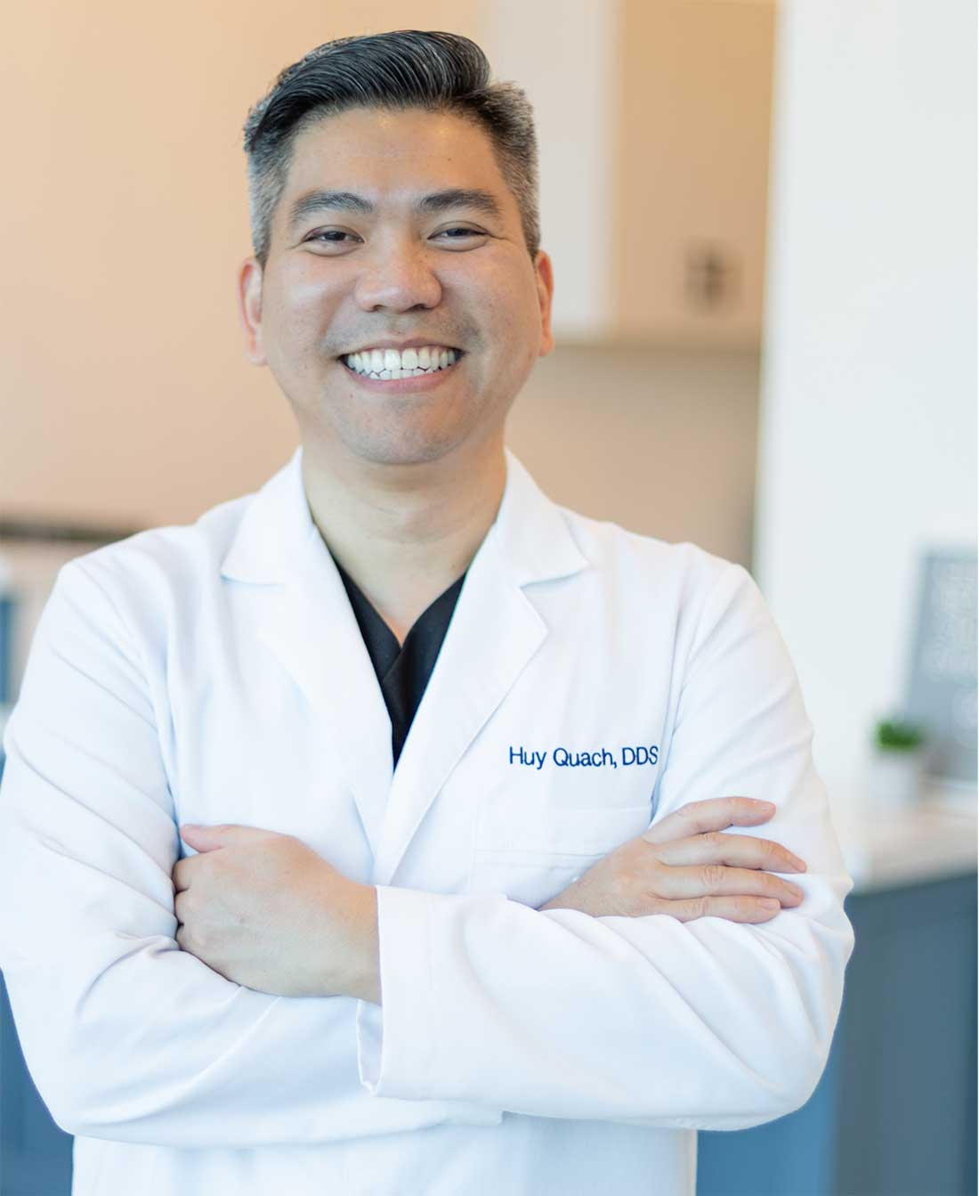 Portrait of Dr. Huy Quach, DDS, smiling in white coat at Rejuvenate Dentistry
