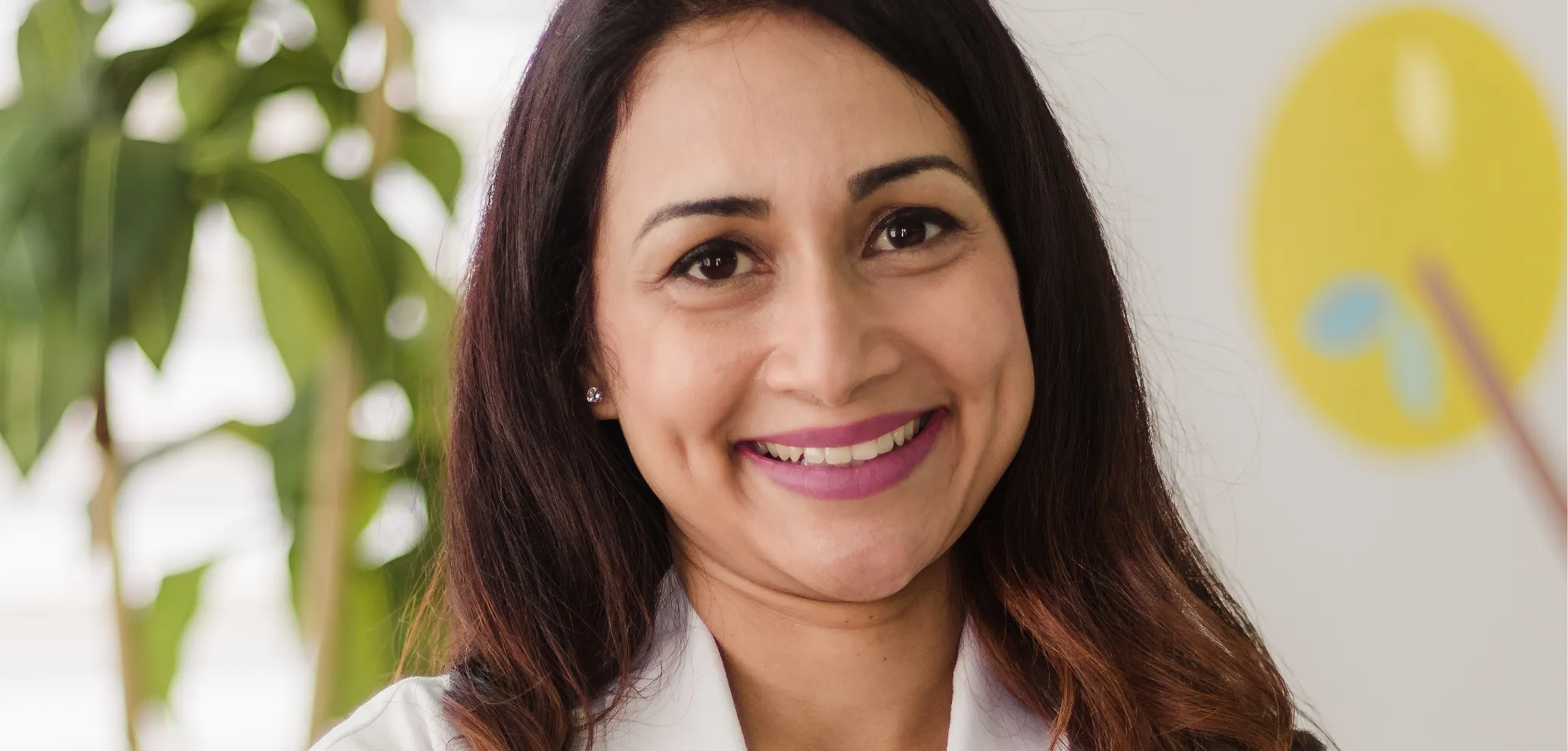 Smiling female dentist in white coat at Castle Hills Pediatric Dentistry in Carrollton, TX