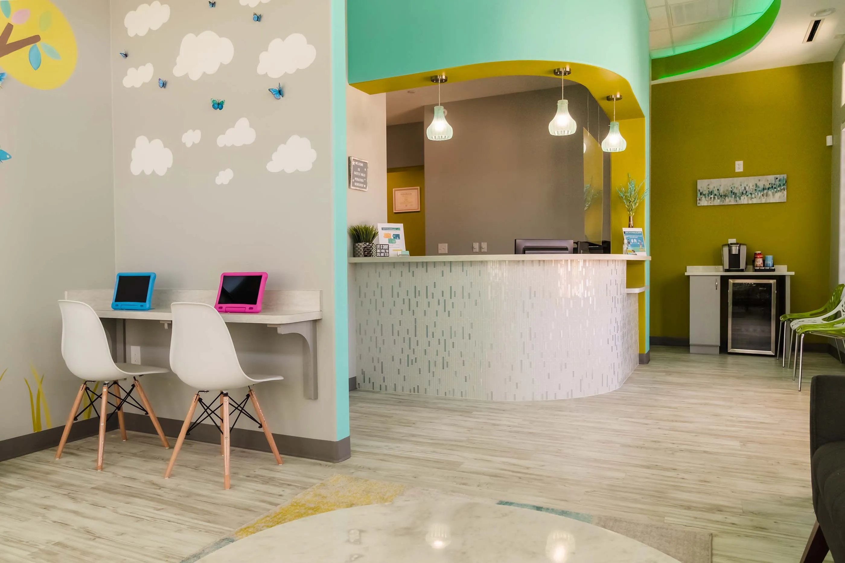 Colorful reception area with tablets and waiting seating at Castle Hills Pediatric Dentistry in Carrollton, TX