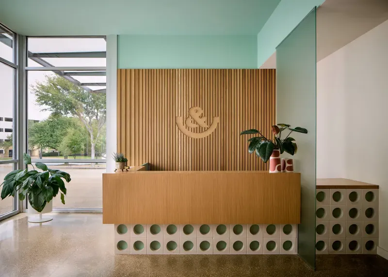 Front desk with logo signage and lobby seating at &Smiles Pediatric Dentistry in Dallas, TX