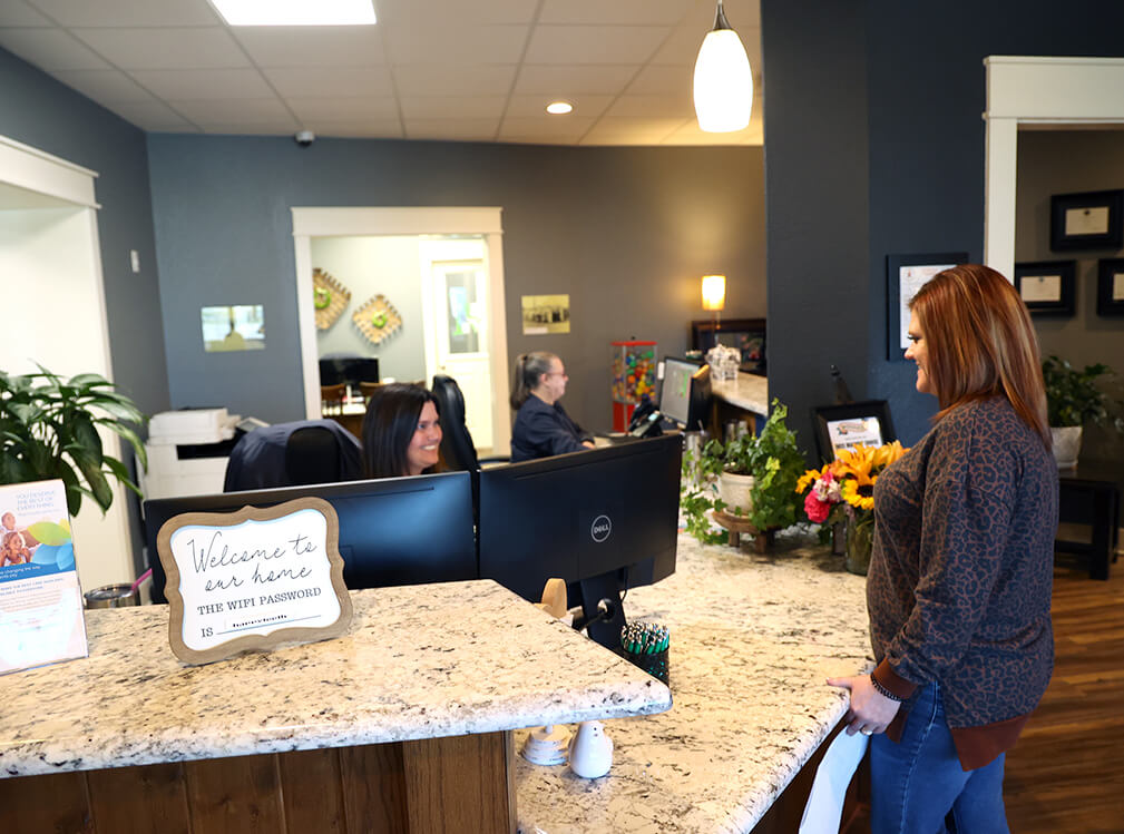 Front desk reception area with staff greeting a patient at Magnolia Dental
