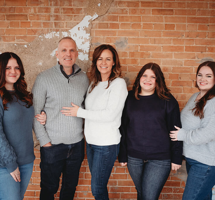 Team photo of Magnolia Dental staff posed against a brick wall