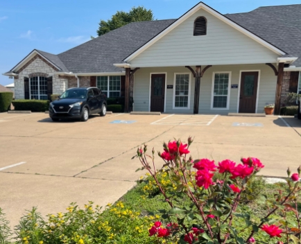Exterior view of Kitt Dental building and parking lot in Flint, TX with flowers in foreground