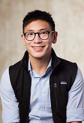Portrait of a dentist wearing glasses and a black vest at the practice
