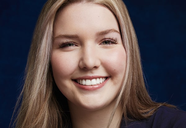 Smiling young woman portrait on dark blue background