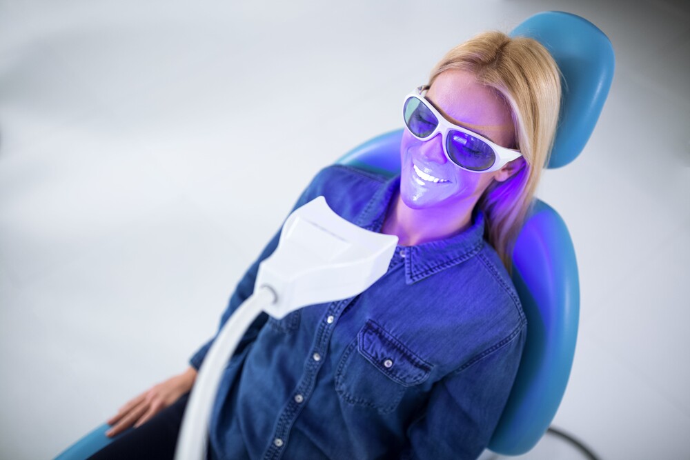 Patient in dental chair wearing protective glasses during a teeth whitening treatment