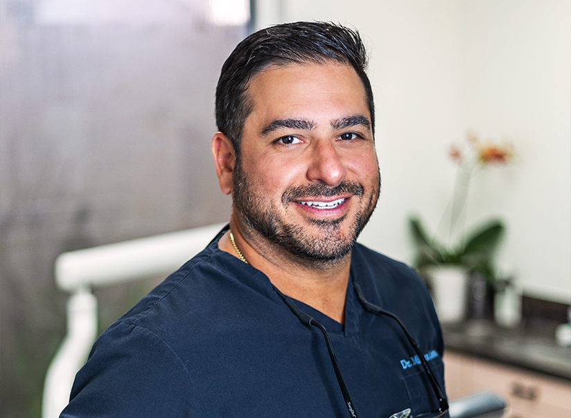 Portrait of a dentist in scrubs smiling at Palm Beach Dental Excellence