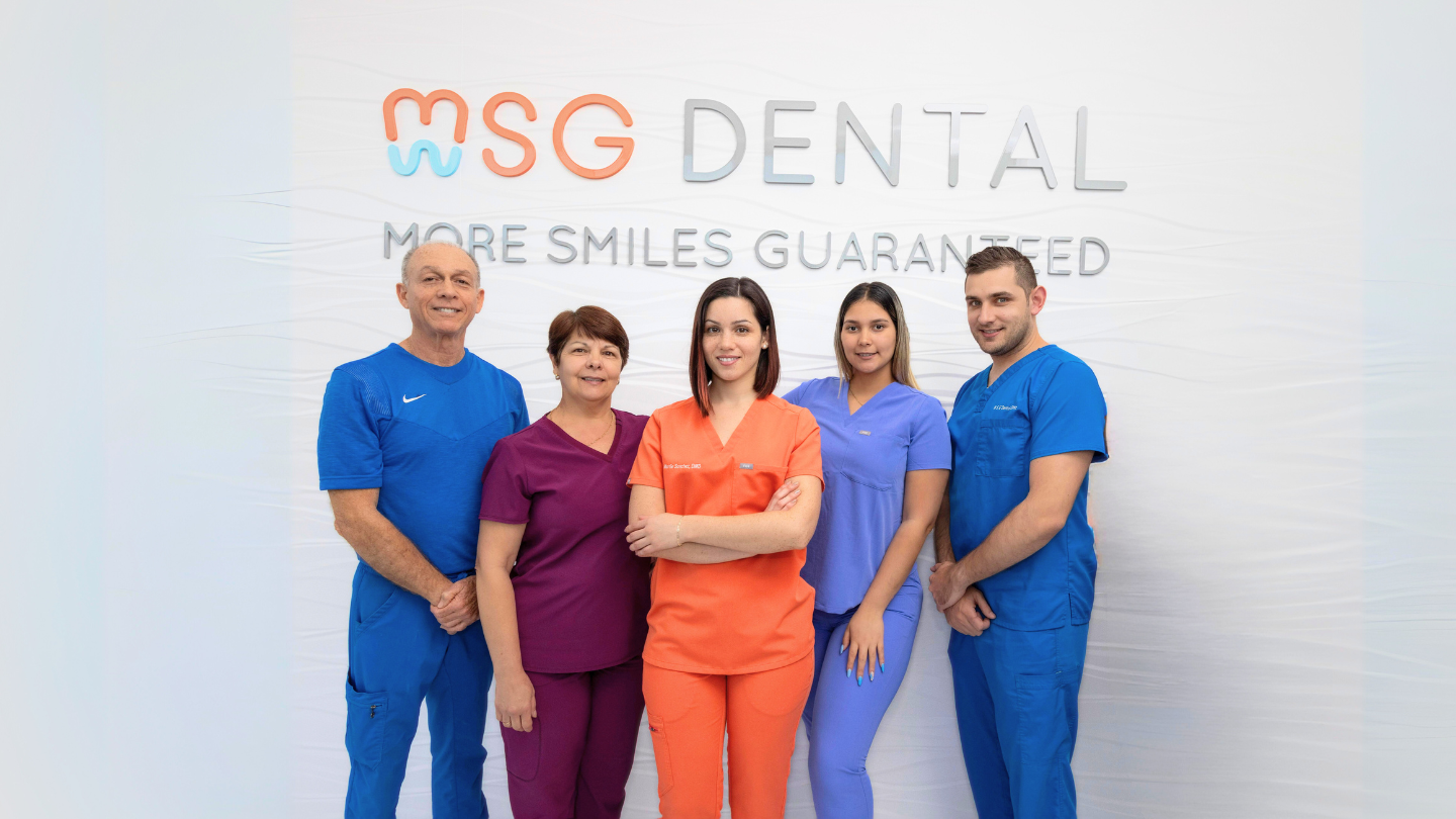 MSG Dental team standing together in front of the practice sign in Miami Lakes