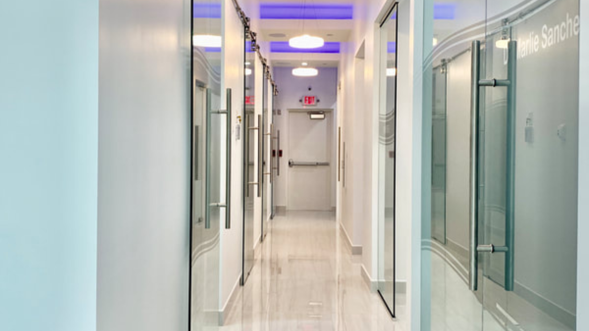 Hallway with glass treatment room doors at MSG Dental in Miami Lakes