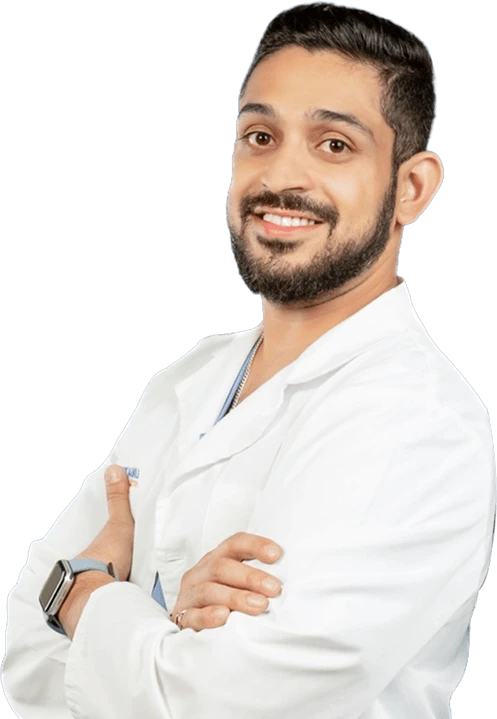 Male dentist in white coat smiling with arms crossed at Kapadias Dental Service