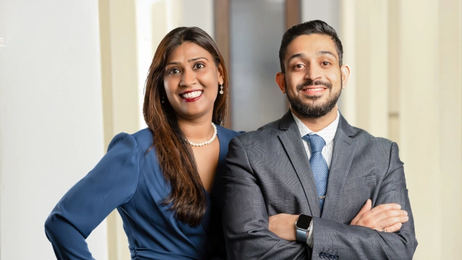 Two smiling dentists in business attire posing together at Kapadias Dental Service in Houston, TX