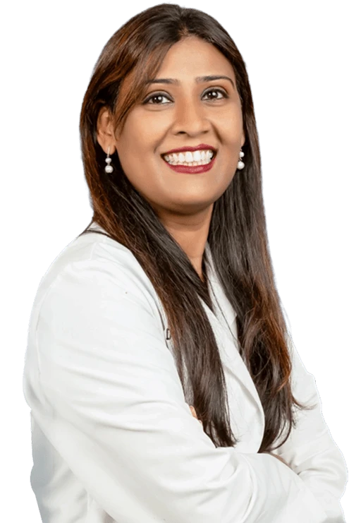 Female dentist in white coat smiling with arms crossed at Kapadias Dental Service