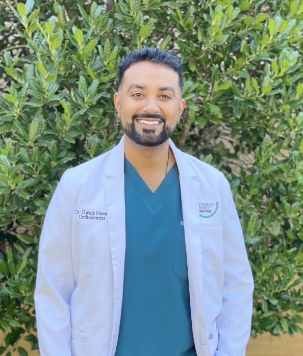 Orthodontist in white coat smiling outdoors at PRO Falls Church PLLC