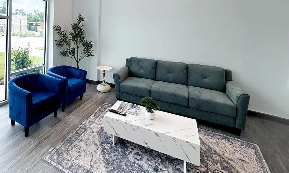 Waiting area with sofa, blue armchairs, and coffee table at Double Tree Dentistry in Magnolia, TX
