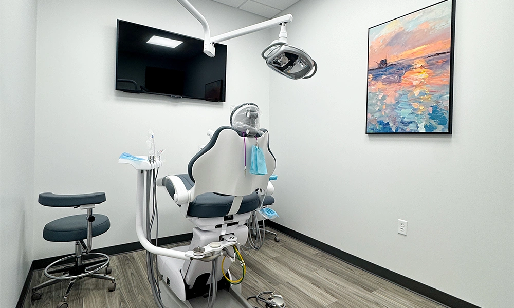 Treatment room with dental chair, overhead light, and wall-mounted TV at Double Tree Dentistry in Magnolia, TX