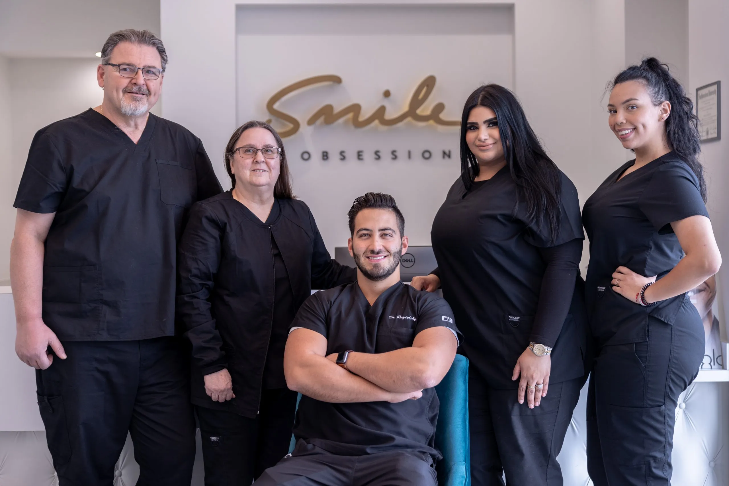 Dentist and team members smiling in front of Smile Obsession logo at the Naperville South office