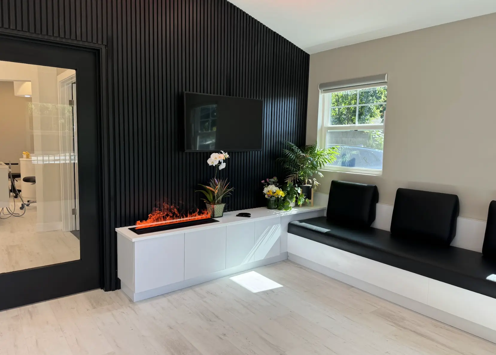 Reception lounge with decorative fireplace, plants, and seating bench at Mona Lisa Smile Dental in Walnut Creek