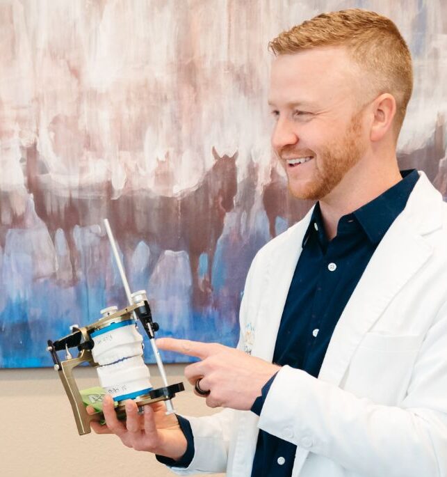 Dentist at Kissing Camels Family Dentistry smiling while holding a dental model mounted on an articulator