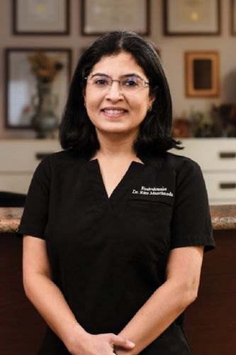 Endodontist Dr. Ritu Manthravadi smiling in black scrubs at Drexel Hill Endodontics