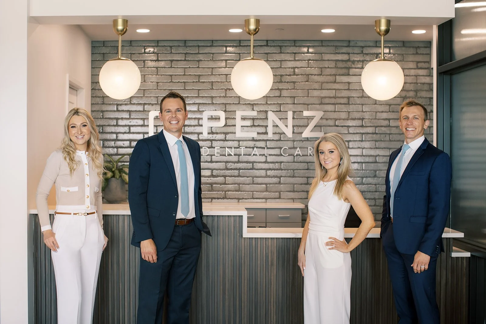 Team members standing at the reception desk at Penz Dental Care in Rochester, MN