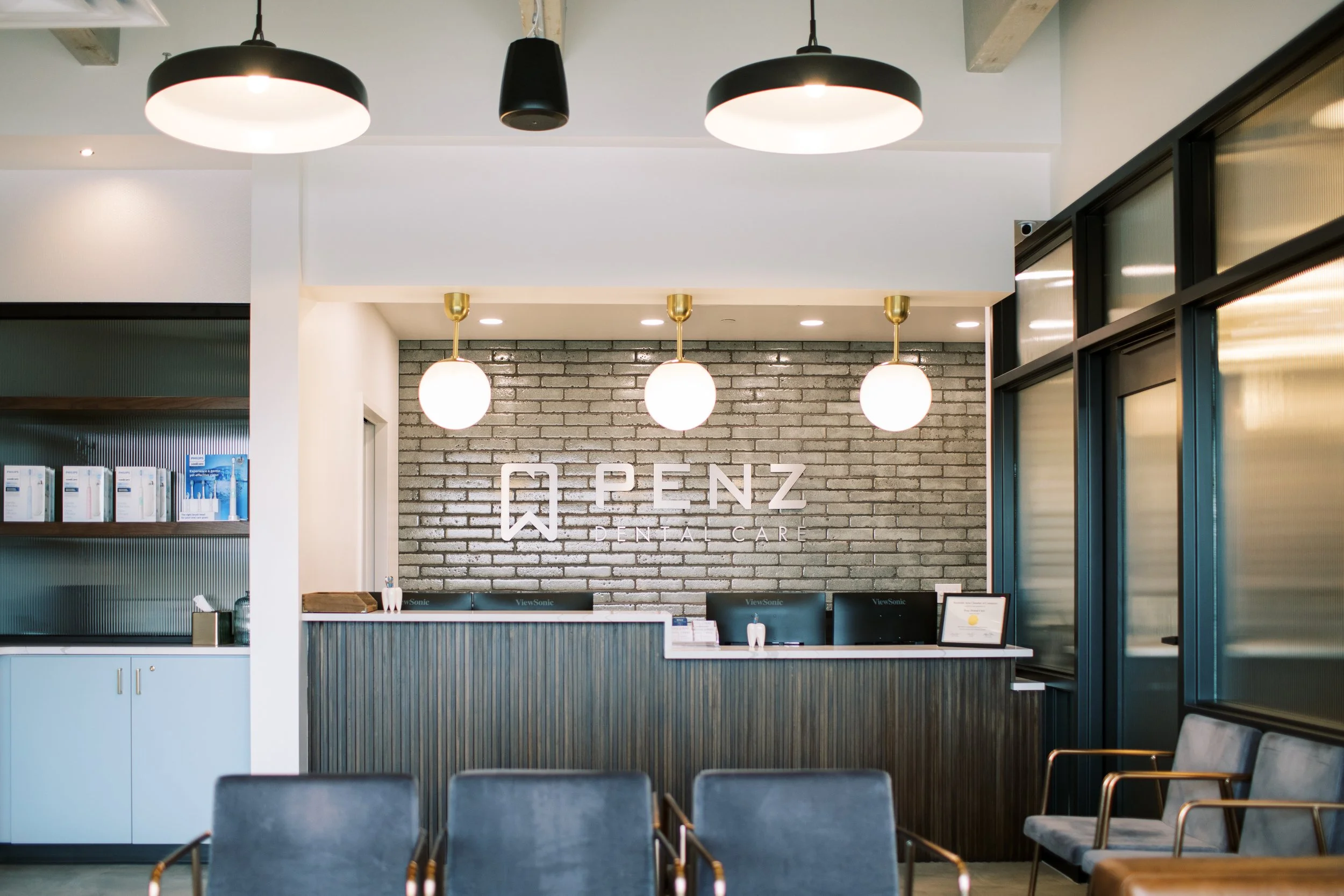 Reception desk with brick accent wall and Penz Dental Care signage