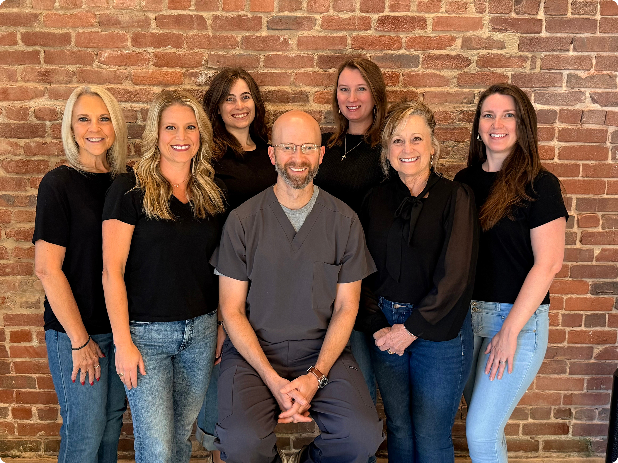 Dr. Aaron Cook and team members posing together against a brick wall at Cook Family and Cosmetic Dentistry in Birmingham, AL