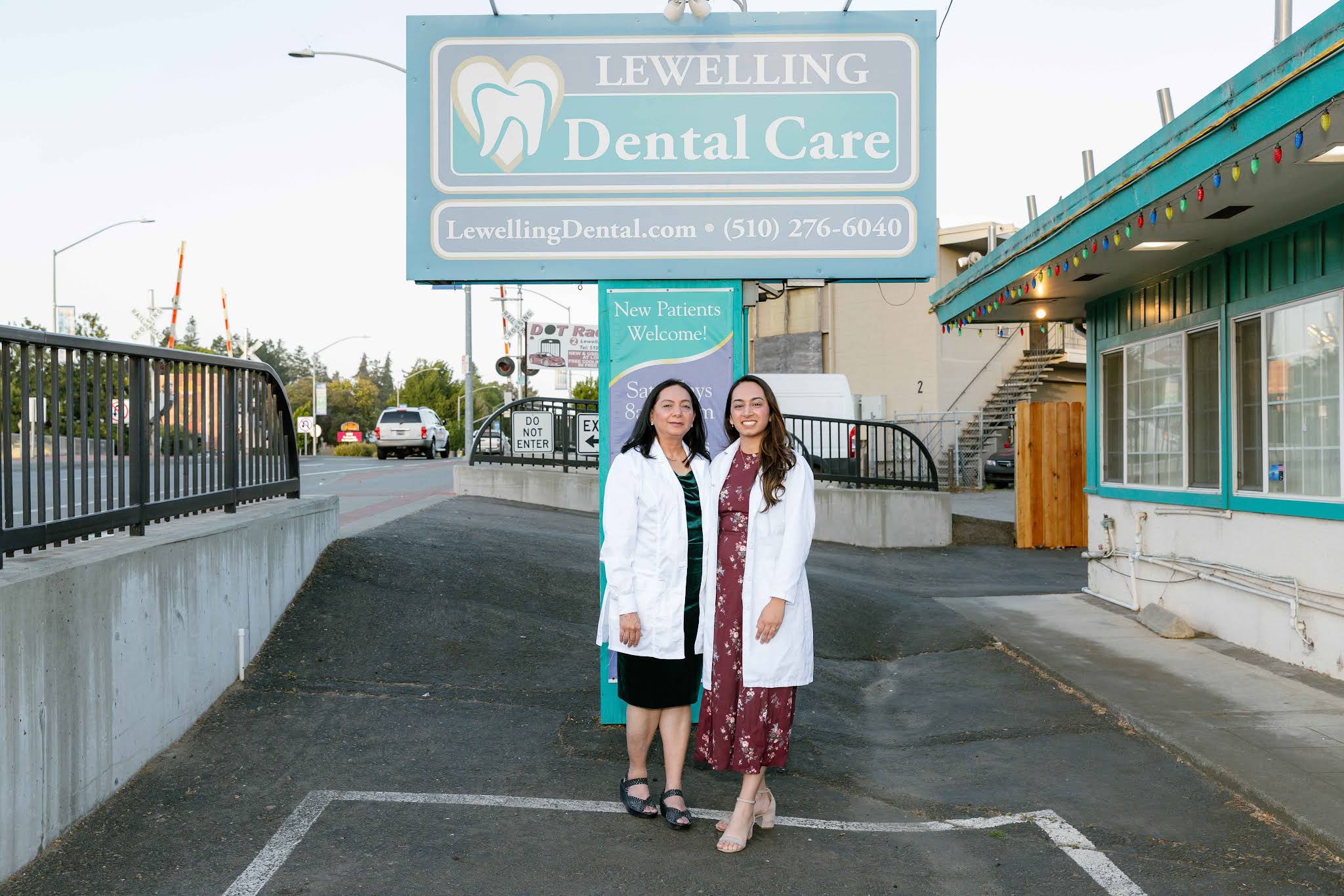 Two dentists in white coats standing beneath the Lewelling Dental Care sign