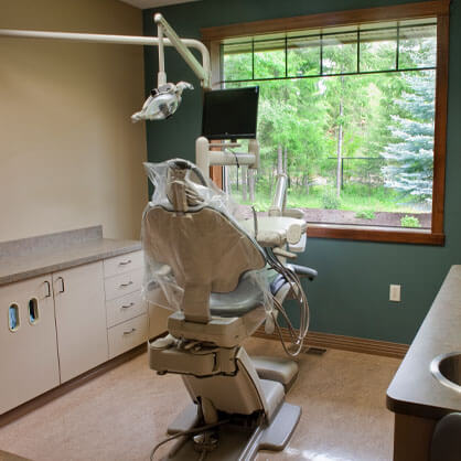 Dental treatment room with chair, overhead light, and window view at Cherilee C Bloom DDS