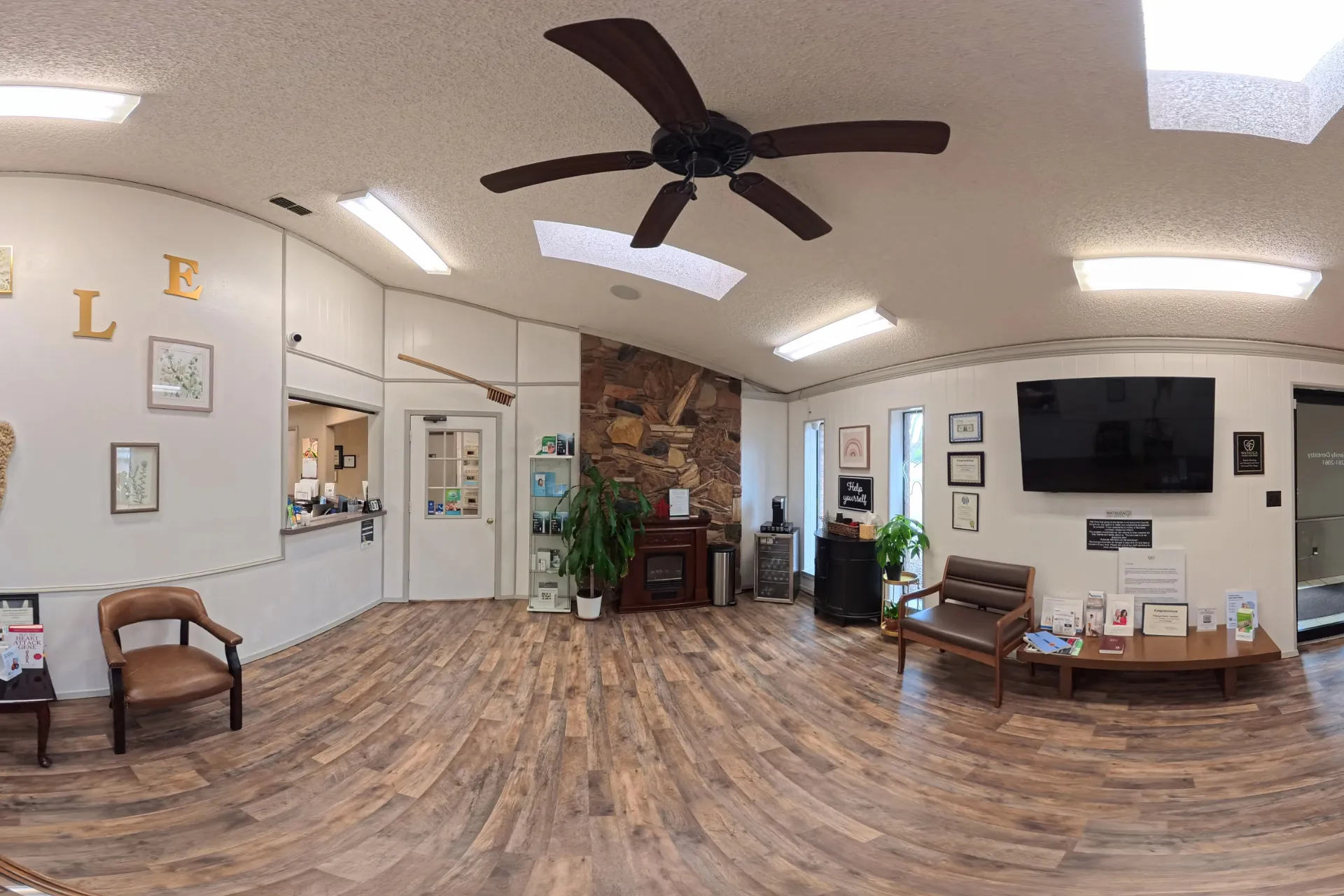 Wide view of waiting area with wood flooring, seating, and TV at Watauga Family Dentistry