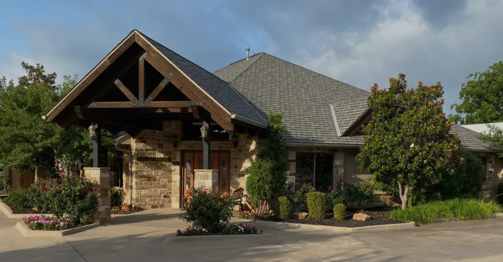 Front entrance view of Four Seasons Dental PA building with covered porch and flower beds