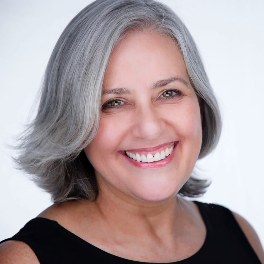 Headshot of a smiling dentist with gray hair against a white background