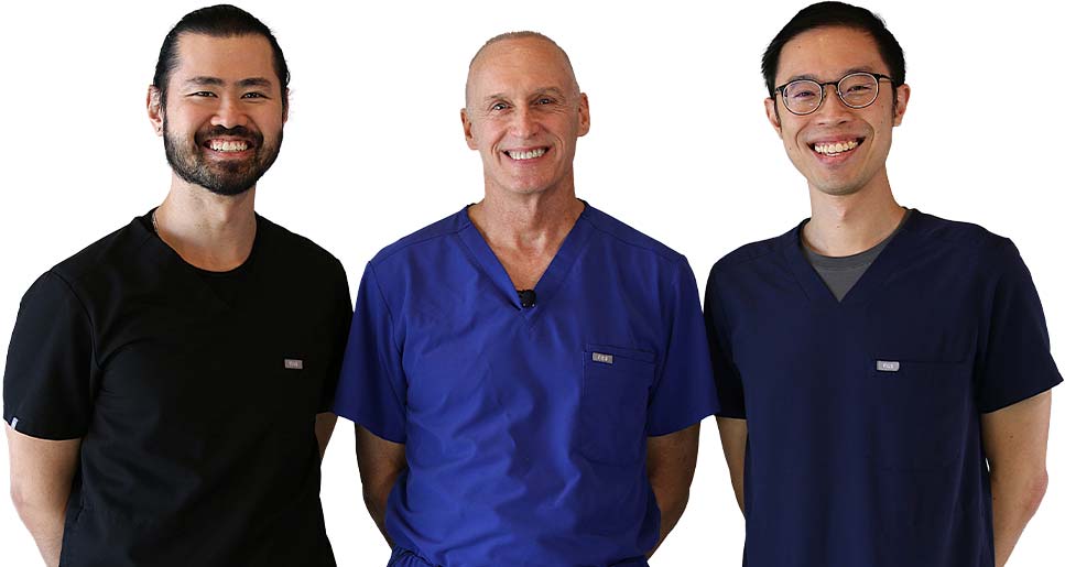 Three smiling dentists from David D McFadden, DMD PA posing together in scrubs